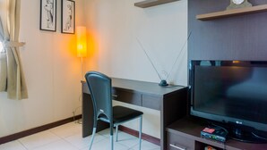 Ein modernes Hotelzimmer mit Schreibtisch, Stuhl, Flachbildfernseher und einer Lampe.