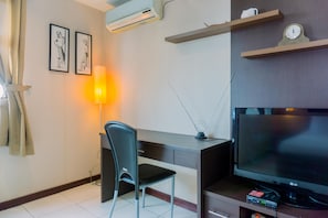 Habitación de hotel moderna con escritorio, silla, televisión de pantalla plana y lámpara.