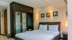 Ein Hotelzimmer mit einem großen Bett, einem dunklen Holzschrank und einem kleinen Nachttisch mit Lampe.