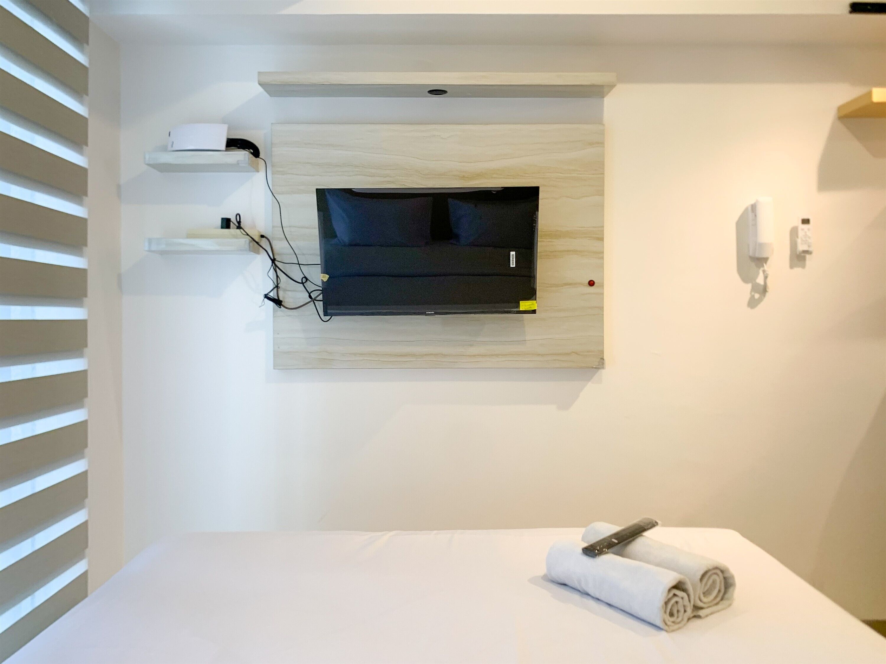 Un baño moderno con una televisión montada, una toalla sobre la encimera y un enchufe.