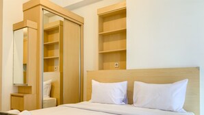 A hotel room with a bed, a wooden wardrobe, and a mirror. - Chic And Cozy Studio Tokyo Riverside Pik 2 Apartment (Teluknaga)