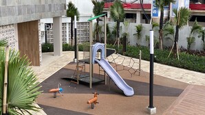A playground with a slide, climbing structure, and swings. - Chic And Cozy Studio Tokyo Riverside Pik 2 Apartment (Teluknaga)