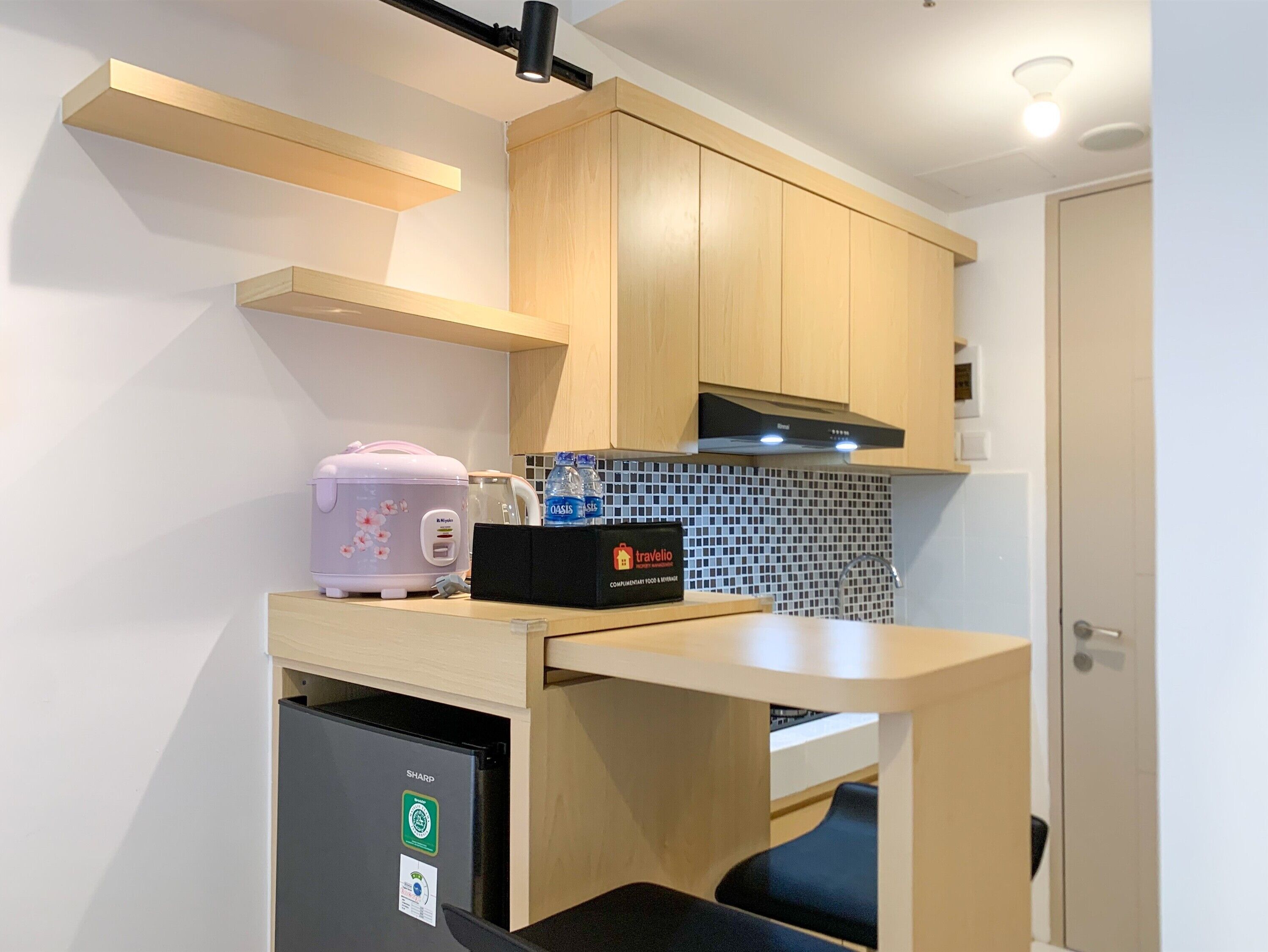 Une petite cuisine équipée d’un plan de travail, d’un grille-pain, d’une bouilloire et d’un réfrigérateur compact.