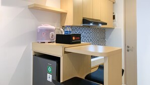 A compact kitchenette with a countertop, a toaster, a kettle, and a compact refrigerator. - Chic And Cozy Studio Tokyo Riverside Pik 2 Apartment (Teluknaga)