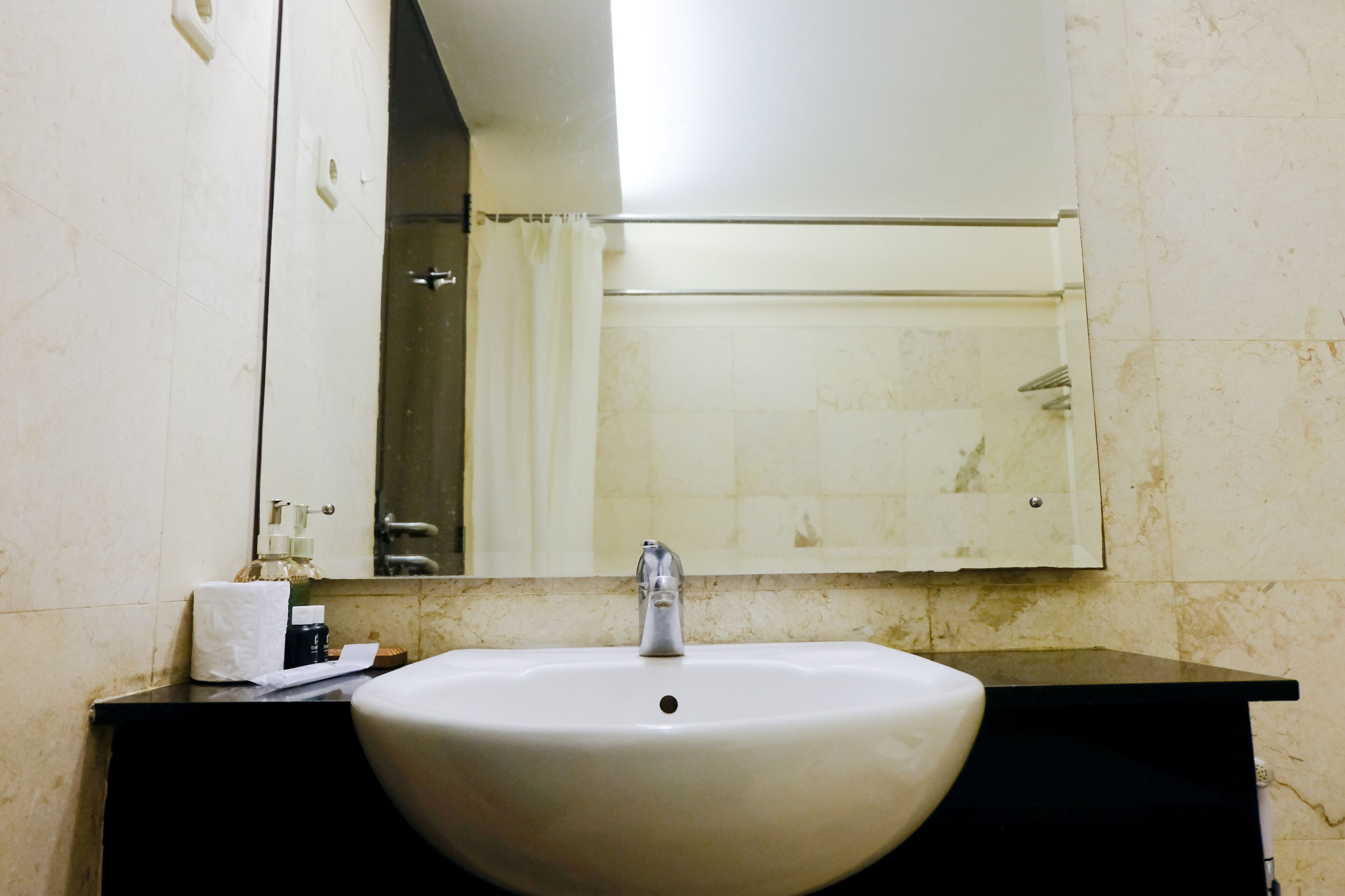 Un bagno con un lavandino bianco, uno specchio e un dispenser per asciugamani.