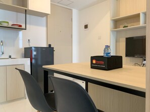 Une cuisine moderne équipée d’un réfrigérateur, d’un évier et d’un coin repas avec une table et des chaises. On peut voir une boîte étiquetée « Travelio » sur la table.