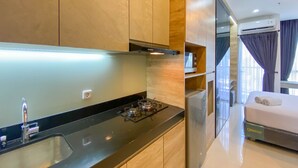 A modern kitchen with a gas stove, sink, and wooden cabinets. - Restful And Comfortable Studio At Ciputra World 2 Apartment (Jakarta)