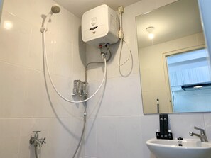 Une salle de bain avec une douche, un lavabo et un miroir.