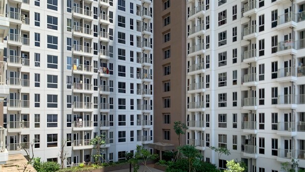 A high-rise residential building with multiple balconies, a central courtyard with greenery, and a mix of white and beige exterior walls. - Luxurious Studio At 7Th Floor Tokyo Riverside Pik 2 Apartment (Teluknaga)