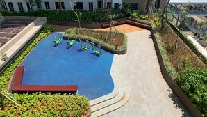 A rooftop pool area with exercise equipment, surrounded by landscaped gardens and a building in the background. - Luxurious Studio At 7Th Floor Tokyo Riverside Pik 2 Apartment (Teluknaga)
