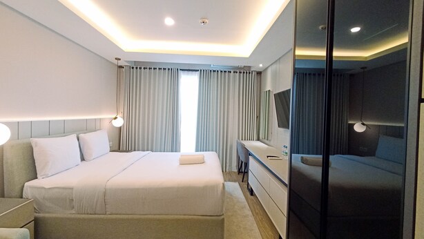 Una habitación de hotel moderna con una cama grande, mesitas de noche, un escritorio y un espejo.