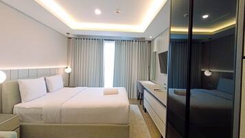 A modern hotel room with a large bed, bedside tables, a desk, and a mirror.