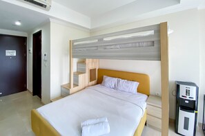 Une chambre d’hôtel équipée d’un lit, d’un bureau, d’une armoire et d’un distributeur d’eau.