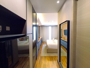 A hotel room with a bed, a desk, a mirror, and a television.
