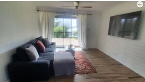 Uma sala de estar com um sofá escuro, uma mesinha e um tapete vermelho.