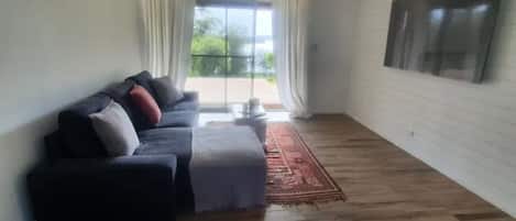 A living room with a dark-colored sofa, a small table, and a red rug.