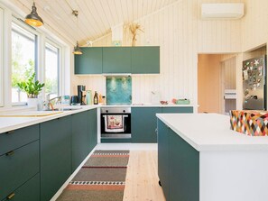 A modern kitchen with dark cabinetry, a central island, and a built-in oven.