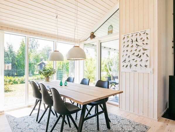 A dining area with a wooden table, black chairs, pendant lights, and a bird poster on the wall.