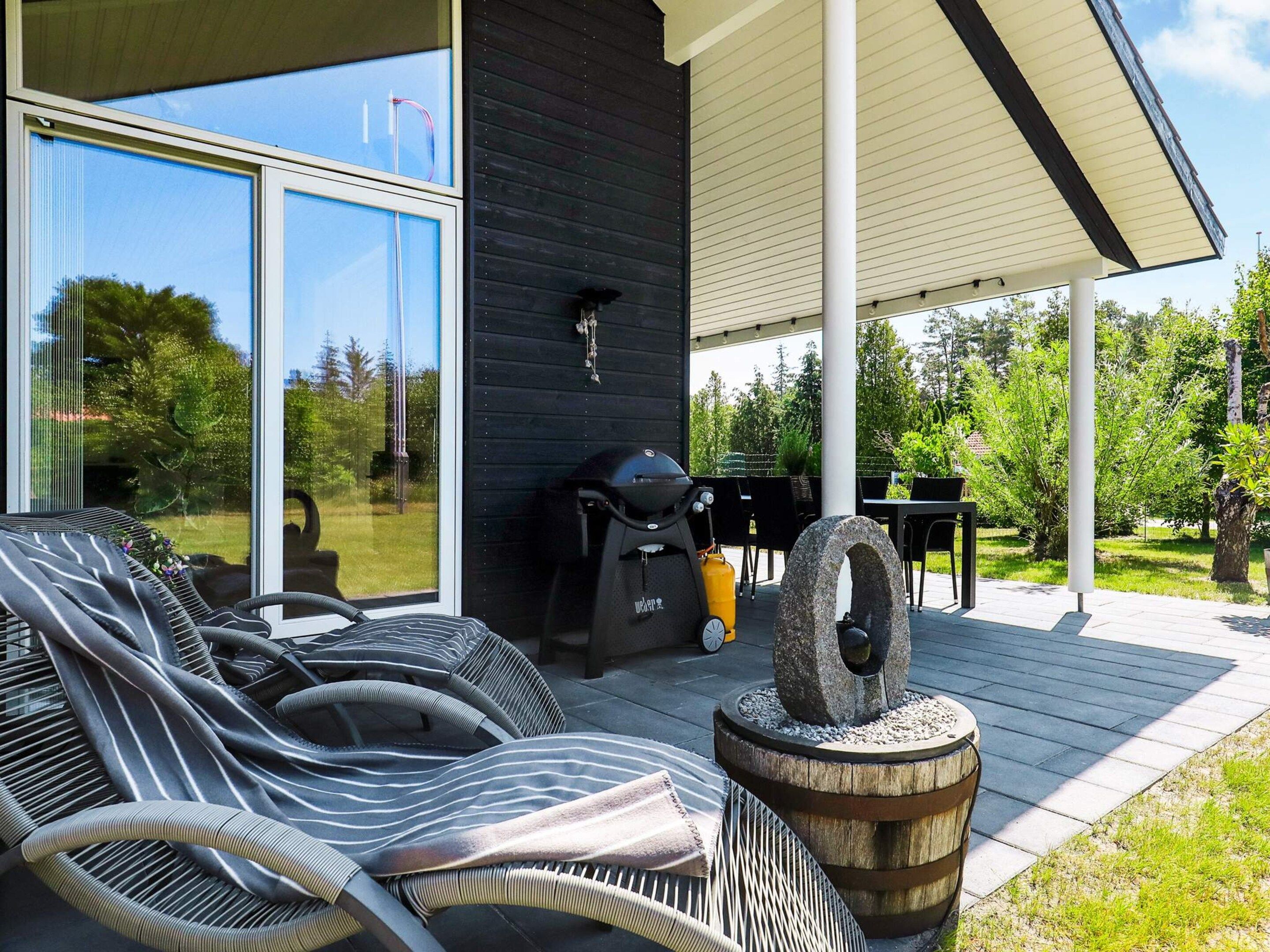 A modern outdoor seating area with lounge chairs and a barbecue grill.