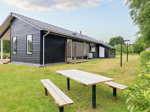 A modern building with a sloped roof, a covered porch, and a picnic table in the foreground.