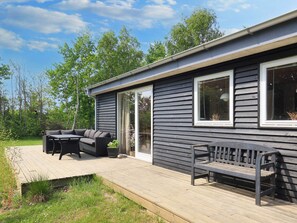 A modern house with a deck, a sofa, and a bench. - 4 Star Holiday Home in Storvorde (Storvorde)