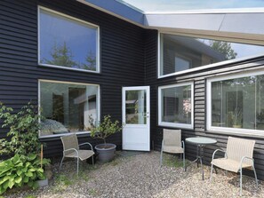 A modern house with large windows, a gravel patio, and outdoor furniture.