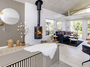 Un salon moderne doté d’un poêle à bois encastré, d’un grand miroir et offrant une vue sur l’extérieur.