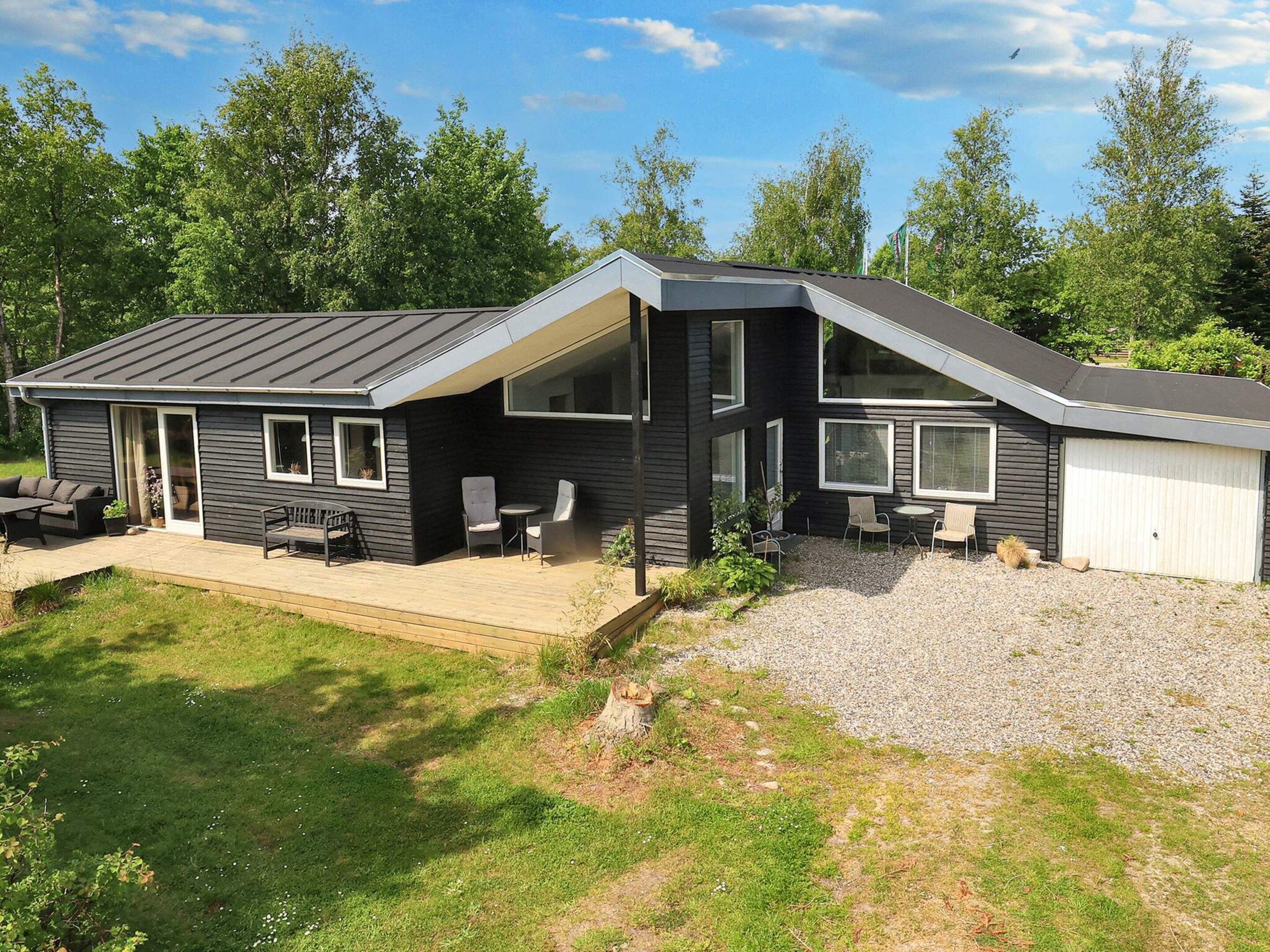 A modern two-story house with a covered patio, a garage, and a landscaped yard.