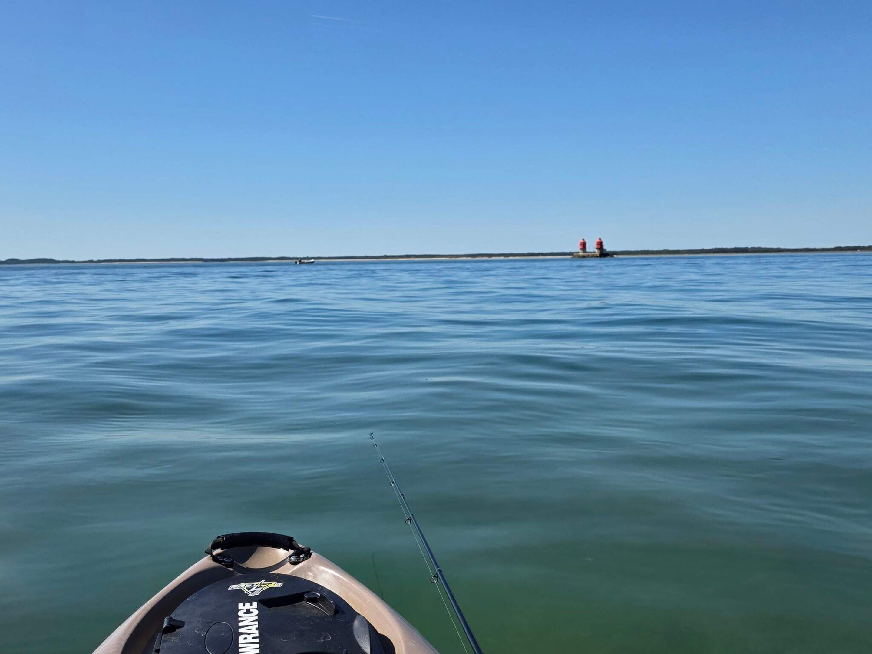 A calm body of water with a fishing rod and a boat.