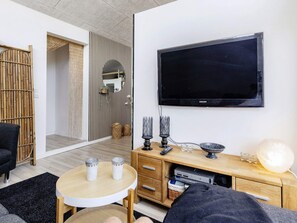 A modern living room with a flat-screen TV, a round coffee table, a sofa, and a wooden cabinet. - 4 Star Holiday Home in Storvorde (Storvorde)