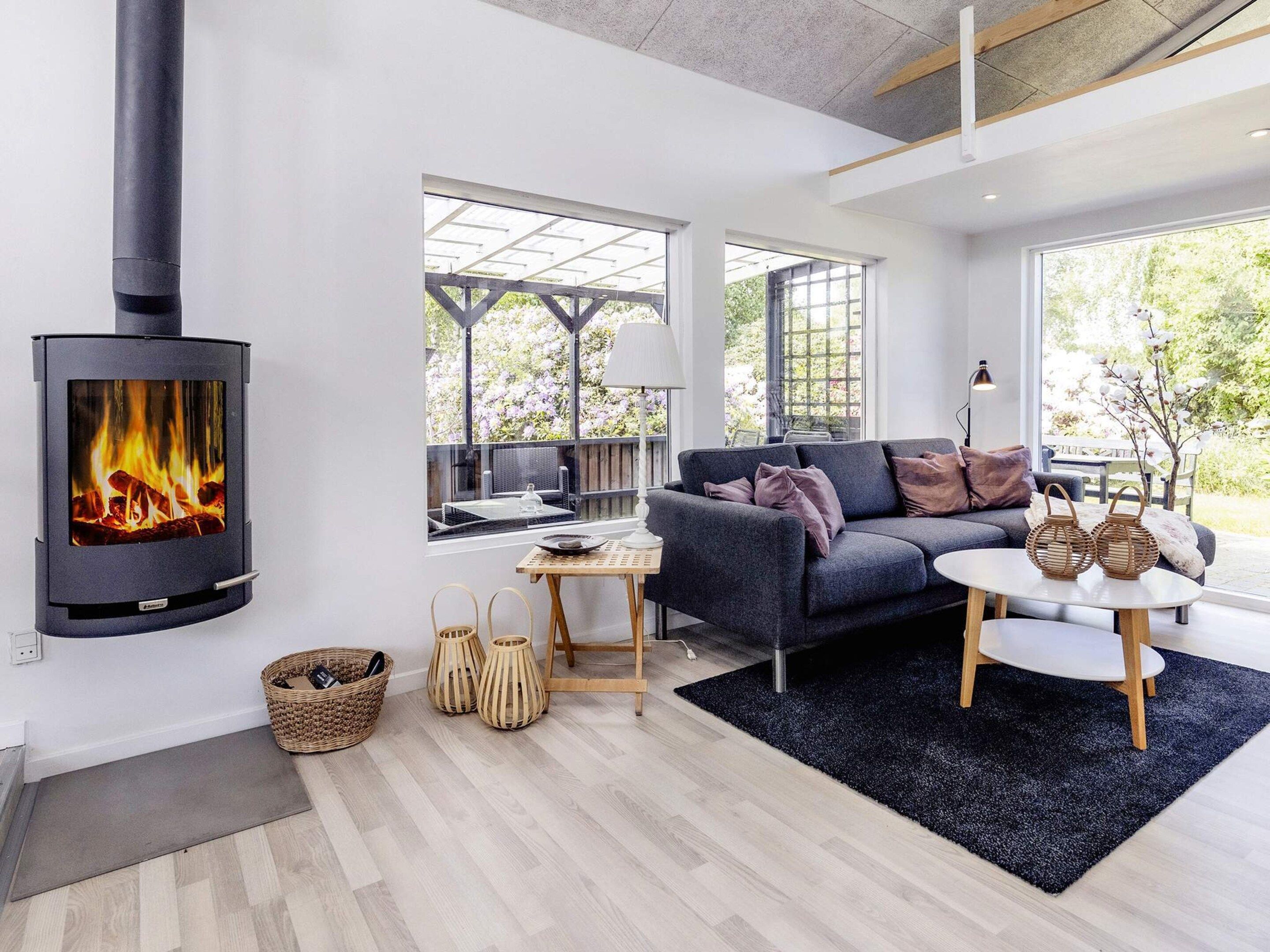 Un salon moderne avec une cheminée, un canapé, une table basse et une vue sur l’extérieur.