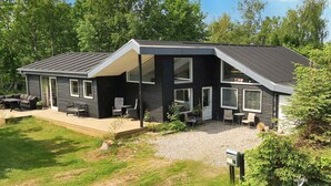 Une maison moderne à deux étages, dotée d’un patio couvert, d’un espace salon extérieur et d’une boîte aux lettres.