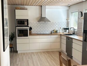 A compact kitchen with white cabinetry, a double oven, a microwave, a sink, and a dishwasher.