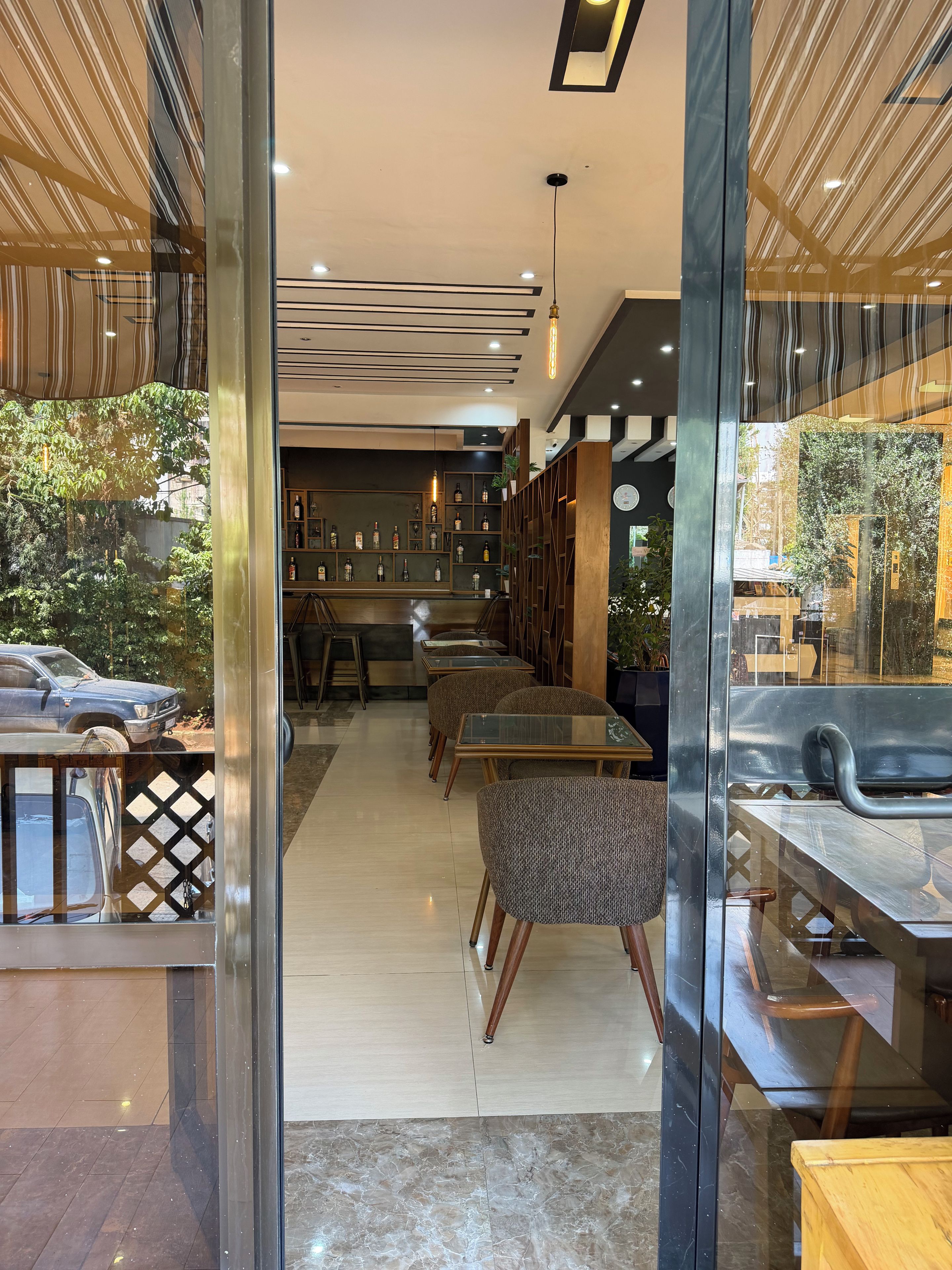 Un intérieur moderne avec une cloison en verre, un espace bar et différents types d’assises.