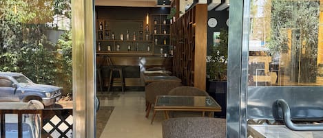 A modern interior with a glass partition, a bar area, and seating arrangements.