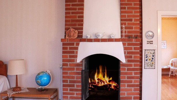 A cozy room with a brick fireplace, a globe on a side table, and a chair. - 6 Person Holiday Home in Dalskog (Dalskog)