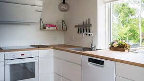 A modern kitchen with white cabinetry, a built-in oven, a dishwasher, and a window providing a view of trees. - 8 Person Holiday Home in Hurup Thy-by Traum (Hurup Thy)
