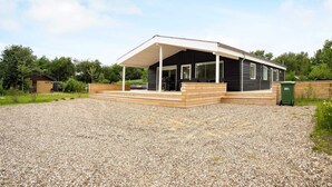 A modern house with a covered porch, a gravel driveway, and a green trash bin. - 8 Person Holiday Home in Hurup Thy-by Traum (Hurup Thy)