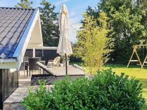 A deck with outdoor furniture, a swing set, and a covered umbrella. - 4 Star Holiday Home in Sydals (Sydals)