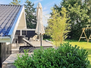 Eine Terrasse mit Gartenmöbeln, einer Schaukel und einem Sonnenschirm.