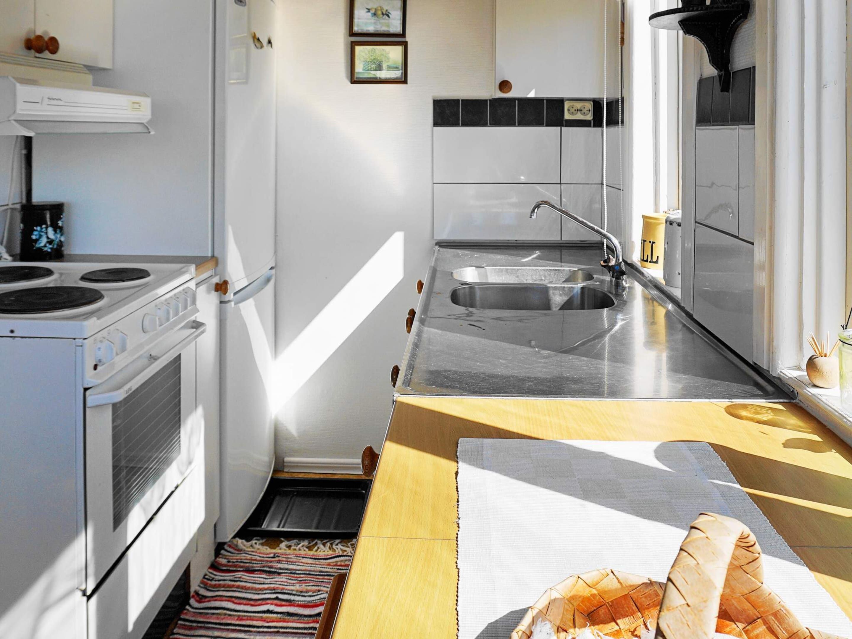 A compact kitchen with a stove, sink, and a small window.