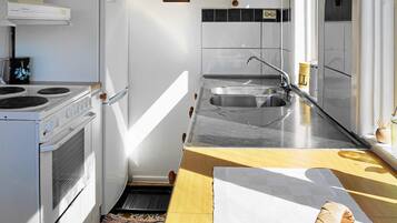 A compact kitchen with a stove, sink, and a small window.