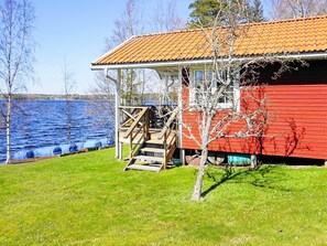 A red building with a porch and a small tree in front.