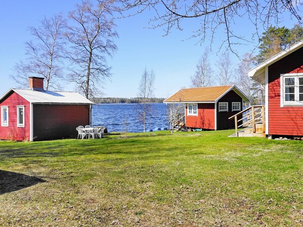 A lakeside cabin with a red exterior, a small deck, and a table with chairs. - 6 Person Holiday Home in Gullspang (Gullspång)