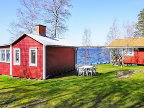 A red wooden house with a white door and windows, a small table with chairs, and a wooden deck. - 6 Person Holiday Home in Gullspang (Gullspång)