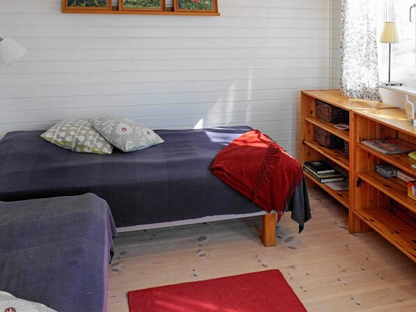 A small, cozy bedroom with a single bed, a wooden nightstand, and a bookshelf.