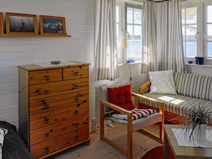 A cozy room with a wooden dresser, a sofa, a chair, and a window with curtains. - 6 Person Holiday Home in Gullspang (Gullspång)