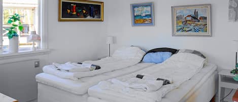 Ein Doppelbett mit weißer Bettwäsche, ein Nachttisch mit Lampe und drei Bilder an der Wand.