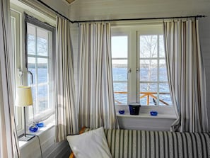 A room with a bed, a window with curtains, a lamp, and a view of a dock and water. - 6 Person Holiday Home in Gullspang (Gullspång)