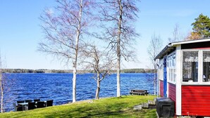 A lakeside cabin with a grassy area, a picnic table, and a view of the lake. - 6 Person Holiday Home in Gullspang (Gullspång)
